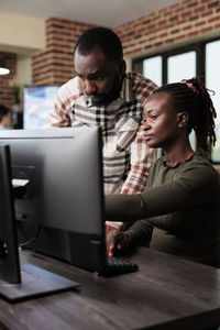 Side view of man using laptop while sitting on table