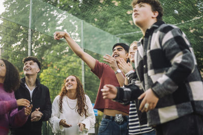 Teenage boy playing basketball with male and female friends at court