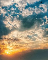 Low angle view of sunlight streaming through clouds