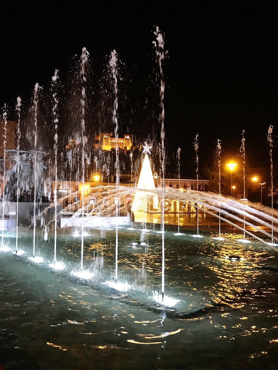 ILLUMINATED FOUNTAIN IN CITY AT NIGHT