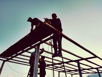 Low angle view of silhouette men against clear sky