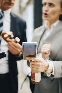 Female business person with smart phone talking to male coworker in city