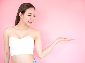 Midsection of woman standing against pink background