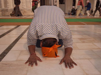 Man kneeling while praying on tiled floor at gurdwara
