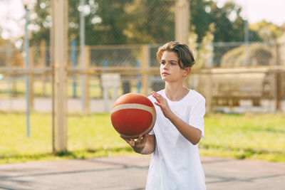 Boy playing with ball in basketball court