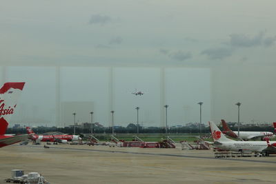 Airplane flying over airport runway against sky