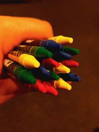 Cropped hand holding multi colored crayons