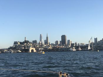 Sea by buildings against clear sky