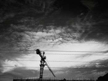 Low angle view of silhouette electricity pylon against sky