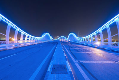 Illuminated light trails on road against sky at night