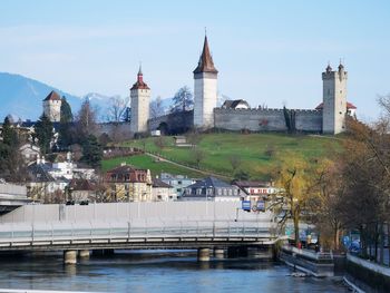 Bridge over river by buildings against sky in city