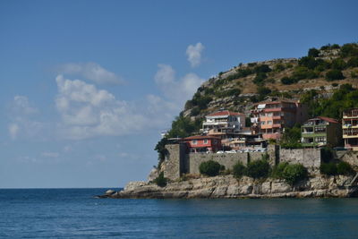 Buildings by sea against sky