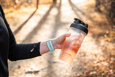 A woman in a black suit holds water with sports nutrition in her hand for outdoor training