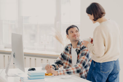 Woman talking with man working at home