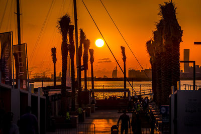 Silhouette of palm trees by sea against sky during sunset