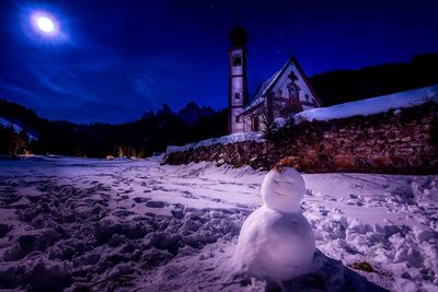 Statue on snow covered field against sky at night