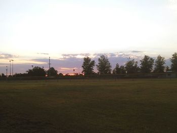 Scenic view of grassy field against sky at sunset