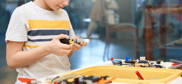 Close-up of boy holding camera while standing on table