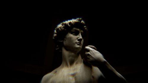 Portrait of young man standing against black background