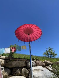 Low angle view of red umbrella against blue sky