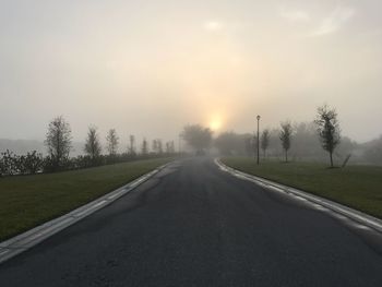 Road amidst trees against sky during sunset