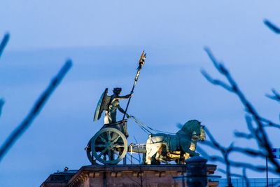 Low angle view of illuminated statue on brandenburg gate against sky at dusk