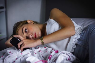 Close-up of young woman using laptop on bed at home