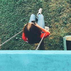 High angle view of woman using smart phone while swinging in park