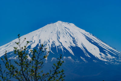 Low angle view of snowcapped mountain against blue sky