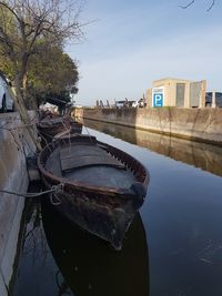 Boat moored in canal against sky