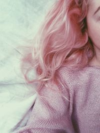 Cropped image of woman with pink dyed hair lying on bed