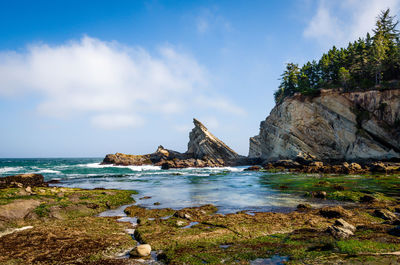 Rock formations at cape arago state park against cloudy sky