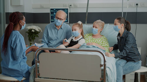 Smiling family with mask talking with doctor at hospital