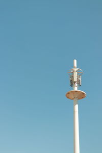 Low angle view of communications tower against clear blue sky