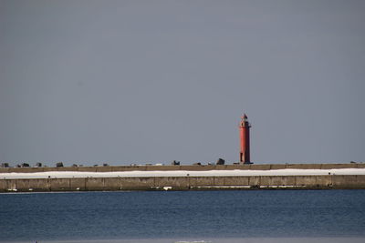 Lighthouse by sea against sky