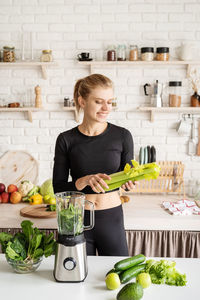 Smiling young woman preparing food in kitchen at home