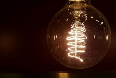 Close-up of illuminated light bulb against black background