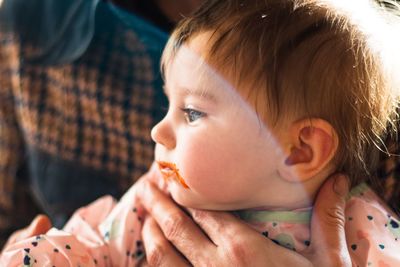 Midsection of person holding cute baby with food on mouth