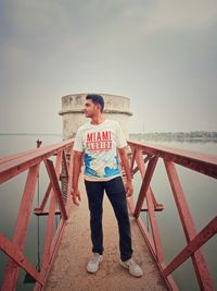 Full length of man standing on railing against sea