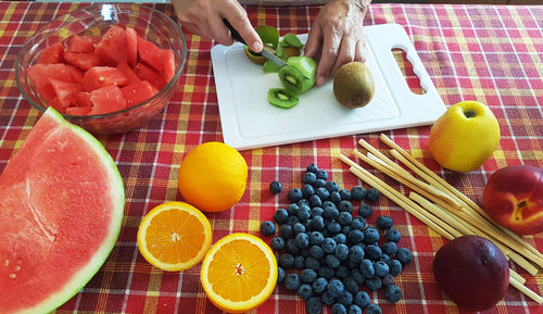 Midsection of woman cutting fruits at table in kitchen