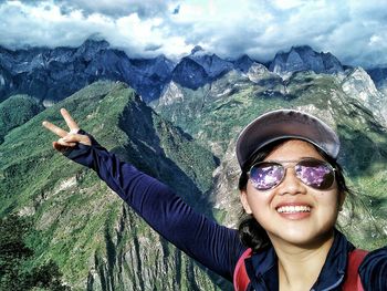 Young woman gesturing peace sign against tiger leaping gorge