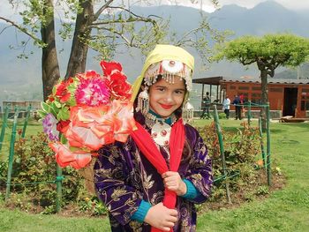 Portrait of smiling young woman standing against trees