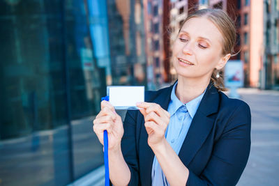 Successful business woman in blue suit and shirt holds badge in her hand