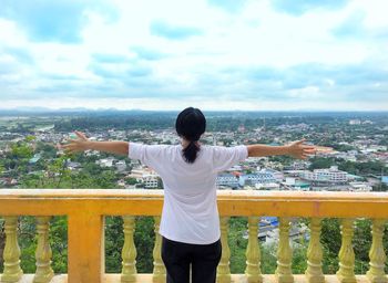 Rear view of man looking at cityscape against sky