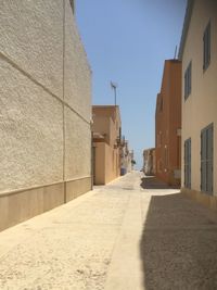 Empty alley amidst buildings against sky