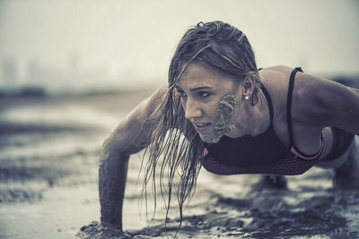 Close-up of athletic woman exercising in mud