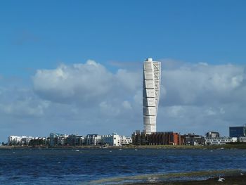 Sea by buildings against sky in city