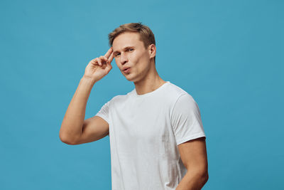 Young man looking away against blue background