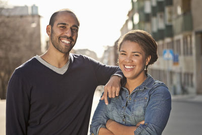 Front view portrait of male friend with arm on female's shoulder