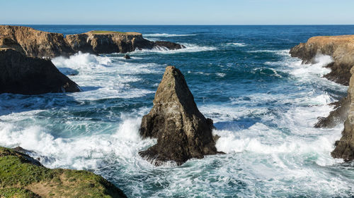 Waves splashing on shore against sky